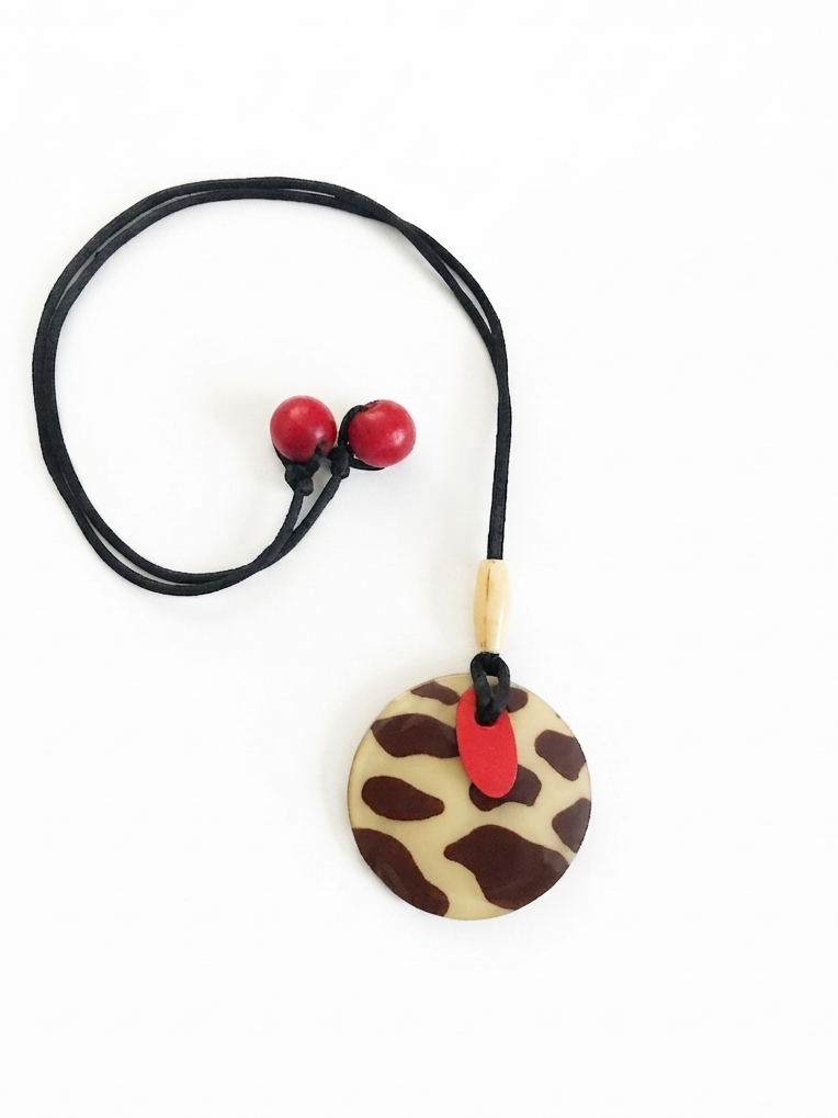 Round wood pendant necklace featuring a cow pattern design and a vivid red accent beads and tie-back closure.