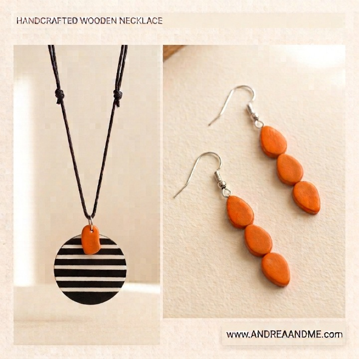 Handcrafted wooden jewelry set featuring a necklace and matching drop earrings. The necklace has a black and white striped circular wooden pendant with an orange accent and small orange wooden beads suspended from a black cord.   Shop www.andreaandme.com