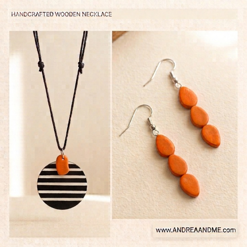 Handcrafted wooden jewelry set featuring a necklace and matching drop earrings. The necklace has a black and white striped circular wooden pendant with an orange accent and small orange wooden beads suspended from a black cord.   Shop www.andreaandme.com